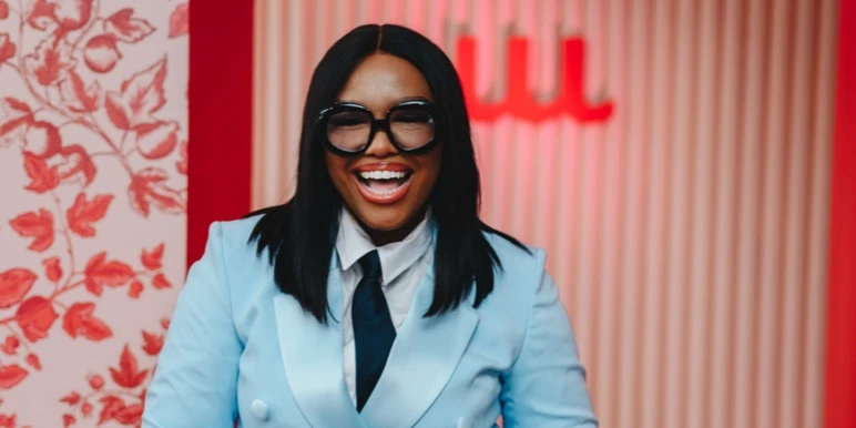 Financial expert Samke Mhlongo and She Owns Her Success Workshop guest speaker, laughing and wearing a tailored light blue suit jacket with a dark tie.