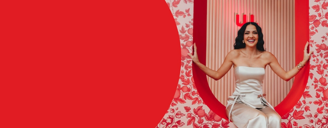 Miss South Africa 2023 Natasha Joubert in the She Owns Her Success studio, smiling and sitting inside a decorative circular cutout next to a red block of text defining 
