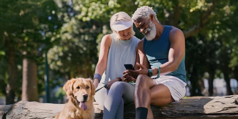 A retired couple sitting outdoors with their dog.