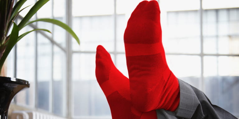 Relaxed feet in red socks on a couch with a glass of milk on the side table.