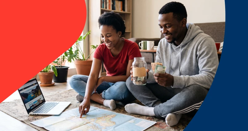 Young South African couple putting money into a savings jar while planning travel on a map, representing smart budgeting to fund big financial goals.
