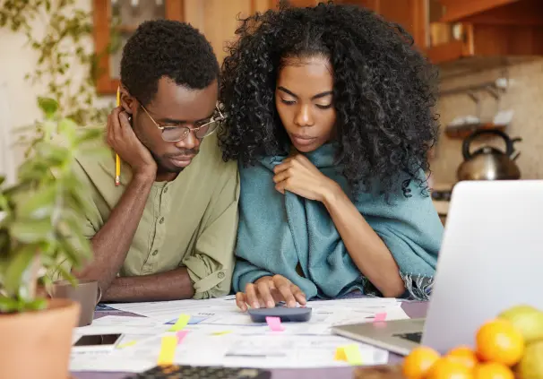 A couple partaking in DIY financial planning, using a calculator and reviewing their retirement annuity statements.