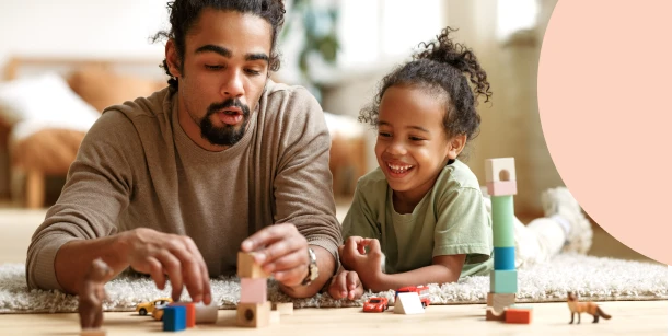 Father and daughter playing with wooden blocks on the floor, representing family estate planning.