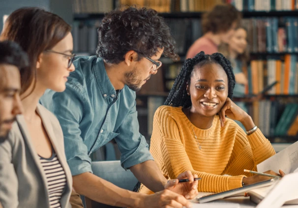 A group of students working together in a library setting, symbolising how an education savings plan supports their academic journey. 