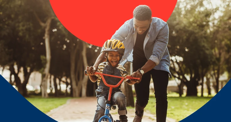 A little boy rides his bicycle while his dad gently pushes him forward. The father feels at ease, knowing he has life insurance in place to protect his family.