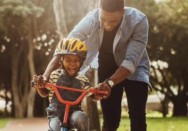 A little boy rides his bicycle while his dad gently pushes him forward. The father feels at ease, knowing he has life insurance in place to protect his family.