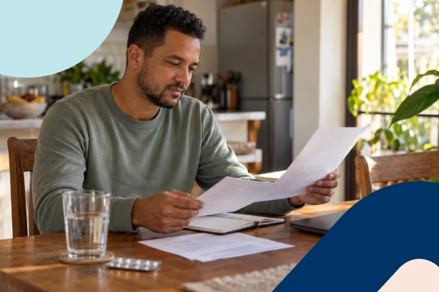 A man seated at his desk reviewing his life insurance policy.