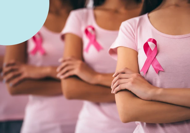 Women standing with pink ribbons on pink t-shirts to highlight breast cancer awareness.