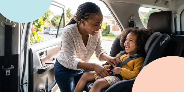 A happy family enjoying a road trip together in a car, with a smiling woman in sunglasses leaning on the open window frame.