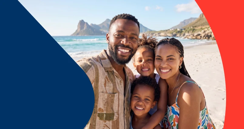 A happy family of four taking a smiling selfie together on a sunny beach.