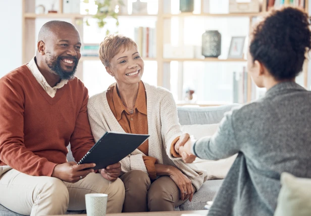 A middle aged couple speaking to their financial adviser about their financial goals during a face-to-face annual review. 