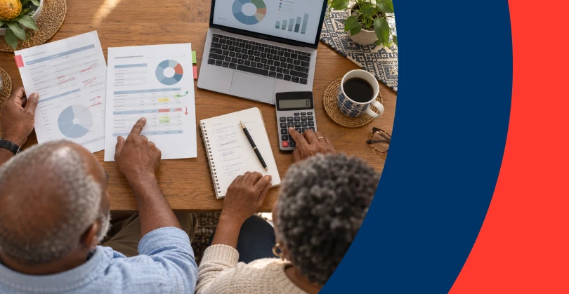 Couple reviewing financial documents and using a calculator to plan their retirement savings.