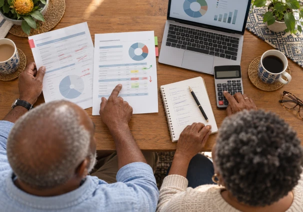 Couple reviewing financial documents and using a calculator to plan their retirement savings.
