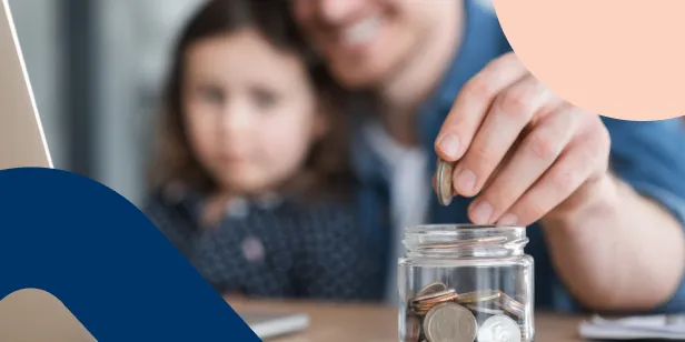 Obscured image of a father teaching his daughter how to save money by adding coins into a savings jar.