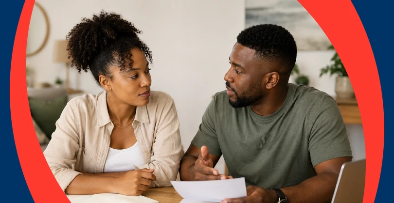 An African couple sit at a table reviewing financial documents together, while discussing their financial goals. 