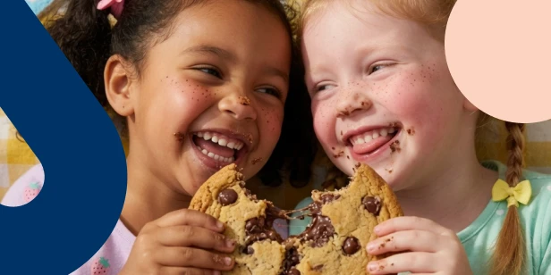 Two children happily sharing a cookie, illustrating the concept of building 