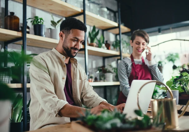 Self-employed small business owner reviewing his retirement annuity statement on a laptop in a plant shop.