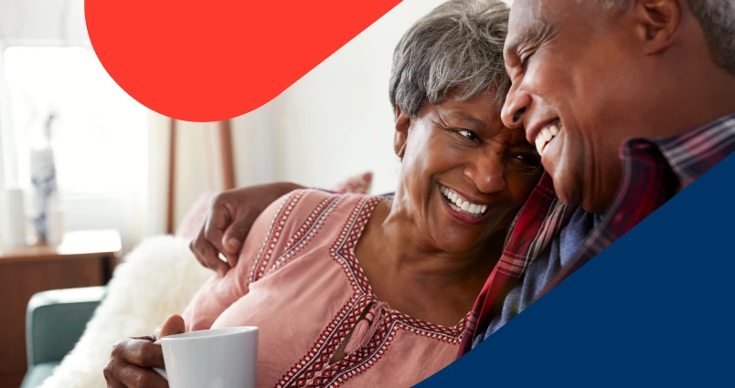A smiling retired couple embracing at home, representing the financial peace of mind achieved through their retirement savings.