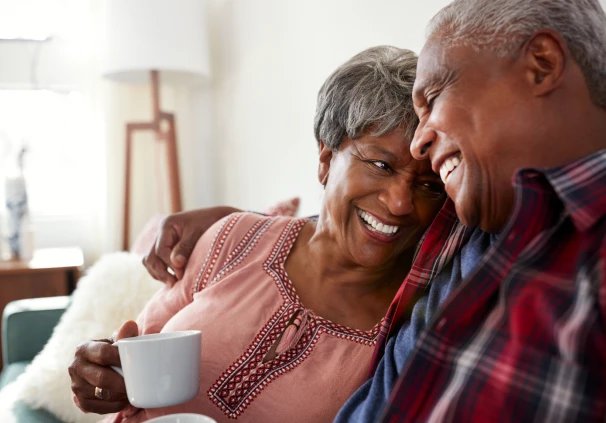 A smiling retired couple embracing at home, representing the financial peace of mind achieved through their retirement savings.