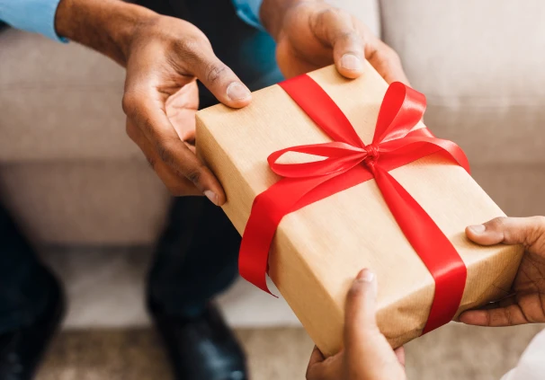 Two people sharing a gift, symbolising how practicing generosity can lead to a healthier and more balanced relationship with money.