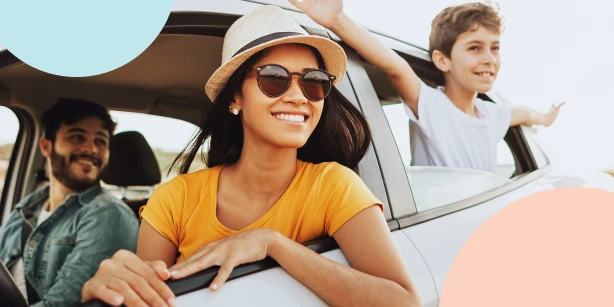 A happy family enjoying a road trip together in a car, with a smiling woman in sunglasses leaning on the open window frame.