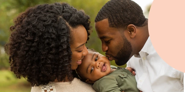 A loving mother and father holding their baby outdoors, representing the hierarchical rules of intestate succession.