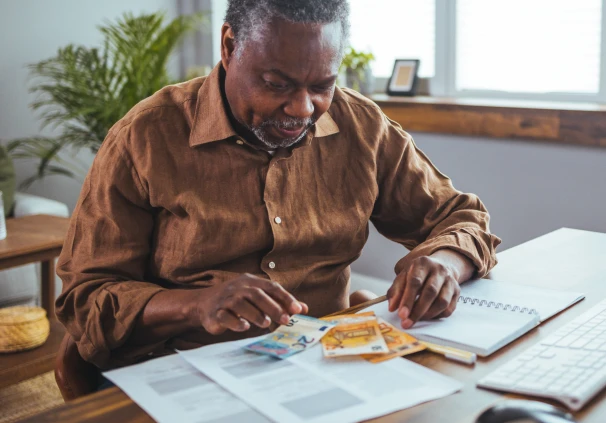 A middle-aged man counting money notes and probably thinking of where to get financial advice.