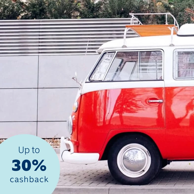 Shiny, glossy red retro Volkswagen transporter van parked on a street pavement in front of residential homes.