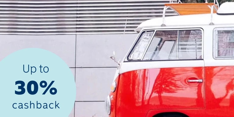 Shiny, glossy red retro Volkswagen transporter van parked on a street pavement in front of residential homes.