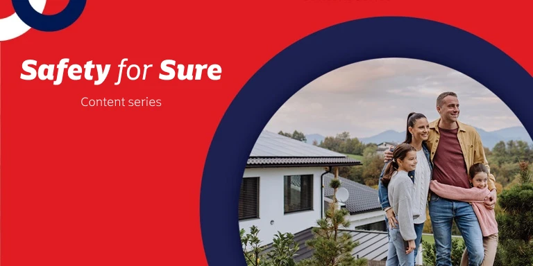 Mom and dad standing in front of their home with their two young daughters.
