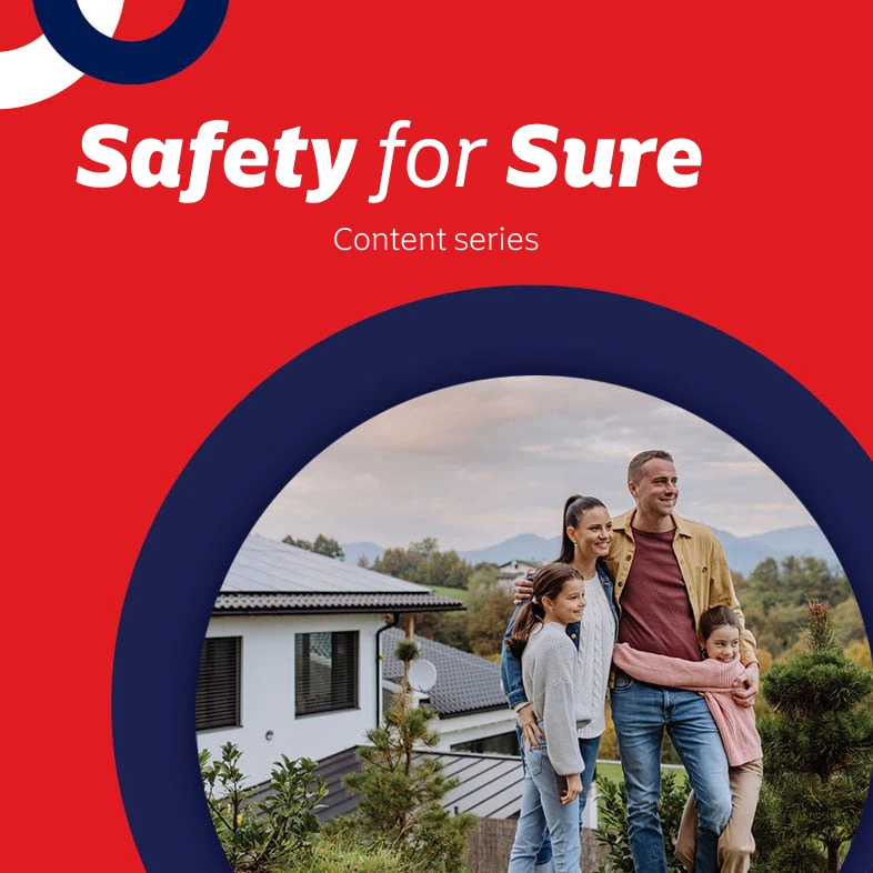 Mom and dad standing in front of their home with their two young daughters.