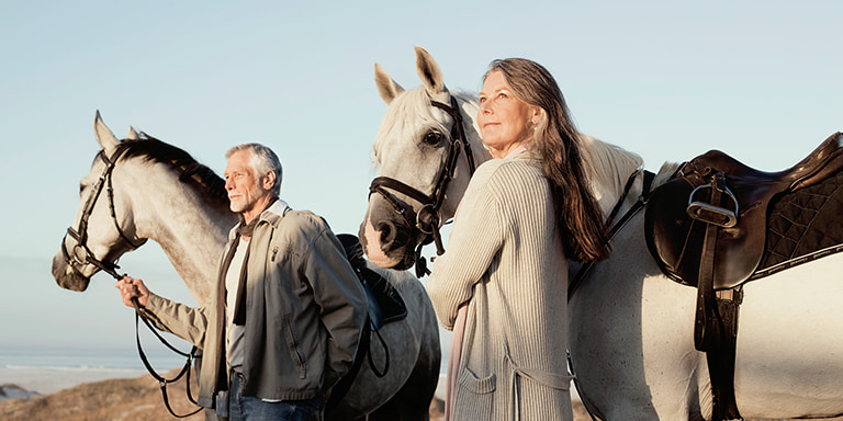 A middle-aged couple, each spouse standing with a horse.