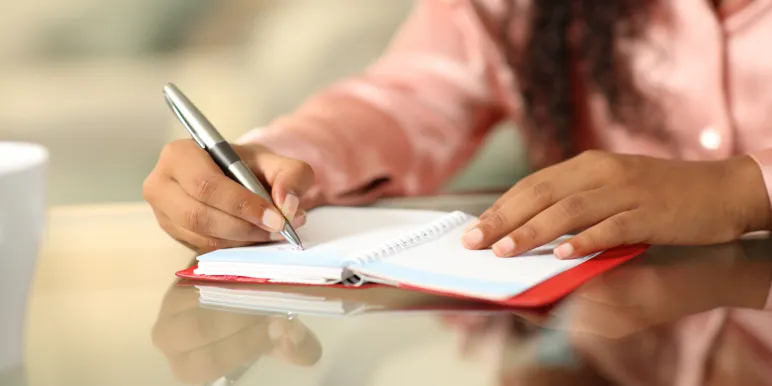 Close-up of a financial adviser writing notes on a notepad.