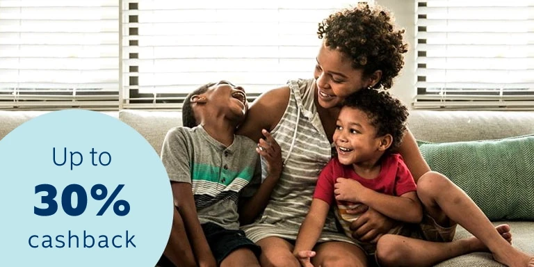 A young mother sitting on a couch and cuddling her two  young toddlers, happy and confident that all her belongings  are insured with a 30% cashback benefit.