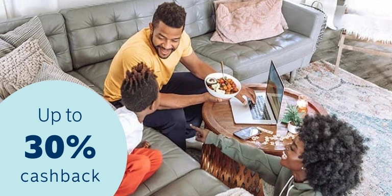 A happy young family sitting in their living area accessing their 30% cashback benefit on a laptop and feeling safe and secure that all their belongs are insured.