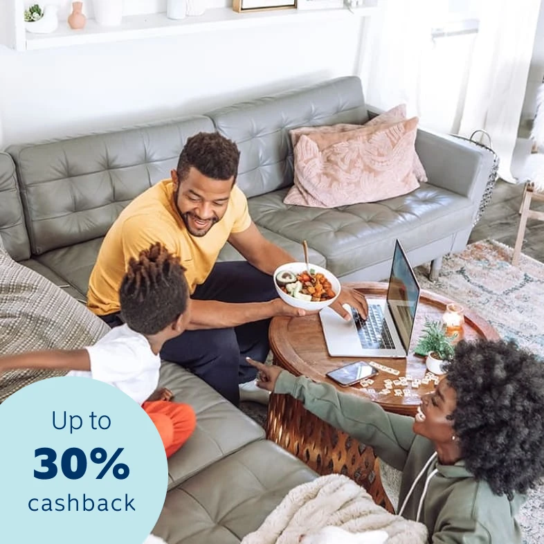 A happy young family sitting in their living area accessing their 30% cashback benefit on a laptop and feeling safe and secure that all their belongs are insured.
