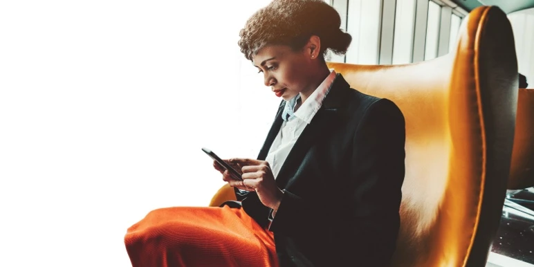 A professional woman in business attire managing her financial advice practice using a mobile device.