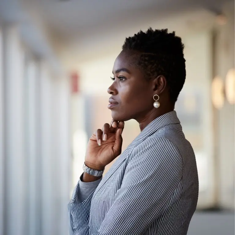 A professional woman in a pinstripe blazer looking out a window, representing financial planning and advisory career opportunities.