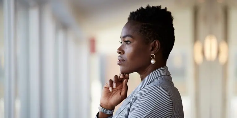 A professional woman in a pinstripe blazer looking out a window, representing financial planning and advisory career opportunities.