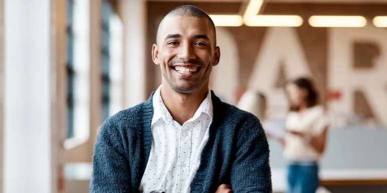A smiling male professional with crossed arms, representing career changers transitioning into a Momentum financial advice career.