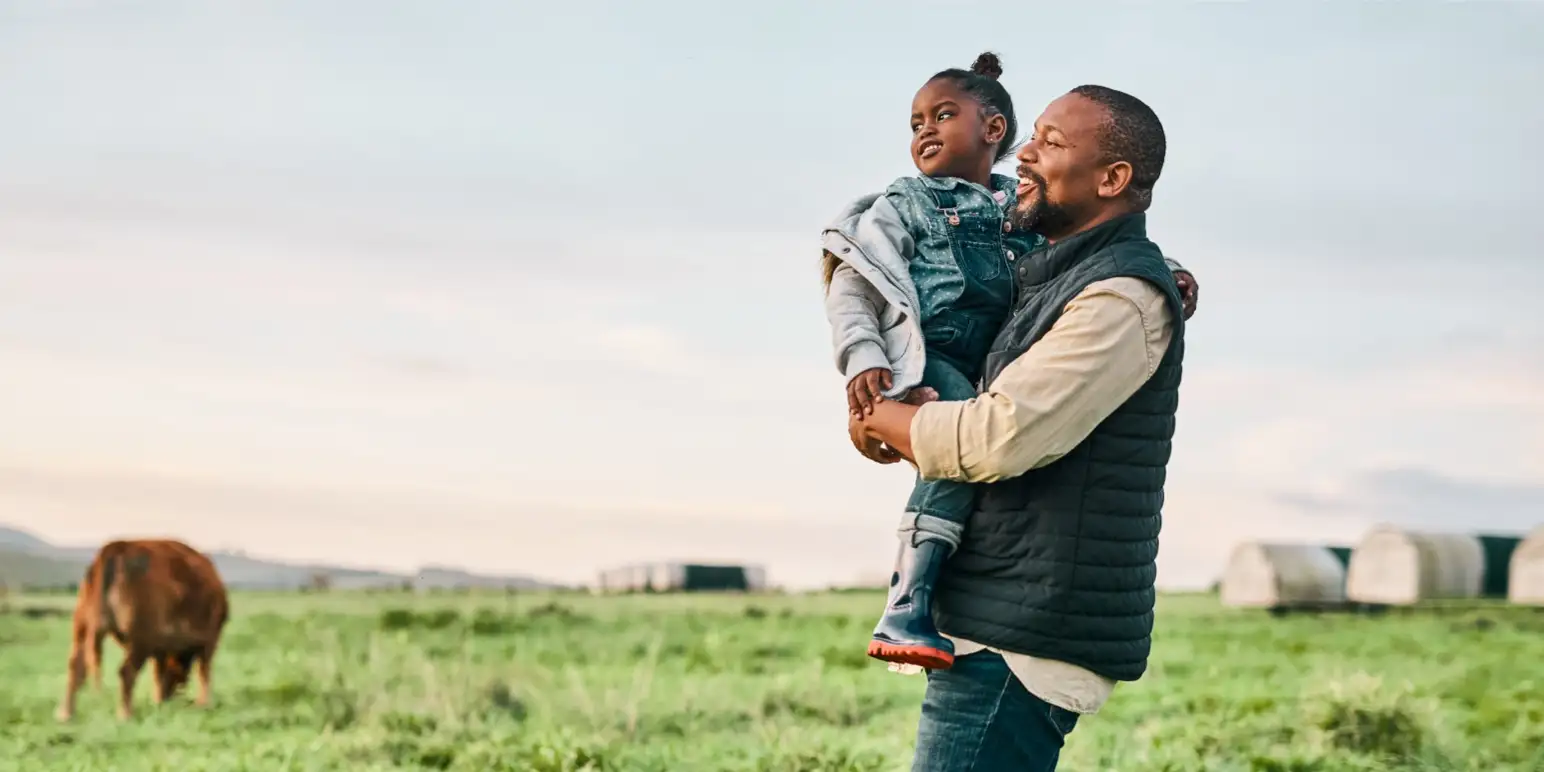Father happily holding his child outdoors representing financial peace of mind and secure post-retirement income through Momentum Annuities.