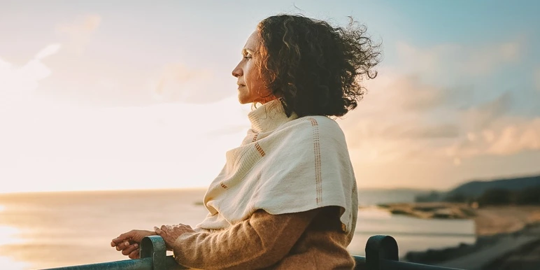 Senior woman looking out at the ocean at sunset representing peace of mind with Momentum Guaranteed Life Annuities. 