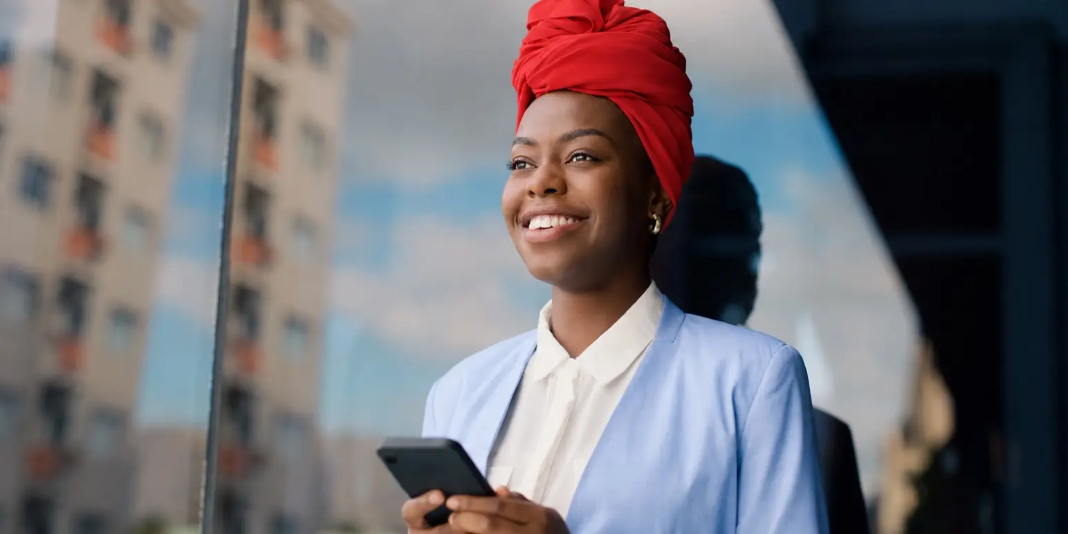 Professional woman with smartphone representing FundsAtWork value-added services and employee wellbeing benefits from Momentum.