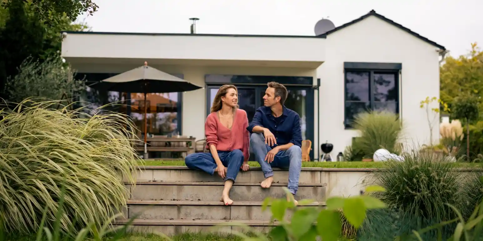 Couple relaxing outside their suburban house representing Momentum pension-backed home loans for property financing.