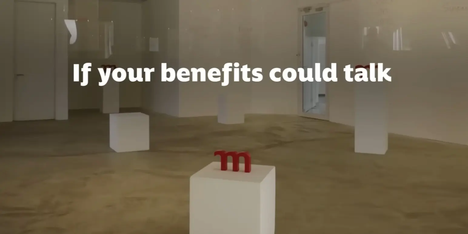 An art gallery space featuring a small, red Momentum 'm' logo block on a pedestal. Overlay text reads: 'If your benefits could talk'.