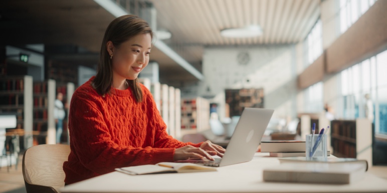 An Asian woman reading through her Momentum Estate Plan on her laptop, smiling confidently that her wishes will be secured, and her family protected.