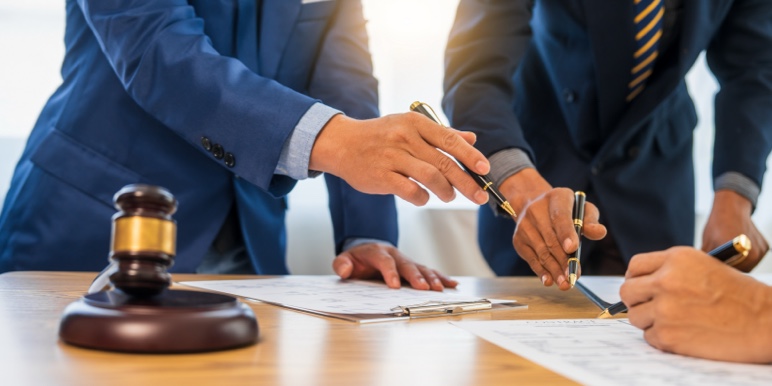 A professional executor and trust administrator discussing the settlement of a deceased estate with a valid Will and gavel on the table.