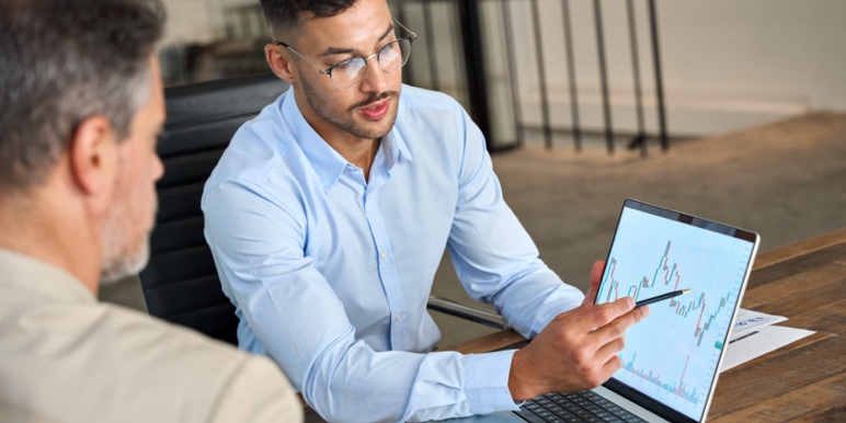 Financial adviser showing a client investment options on a tablet, representing wealth growth.