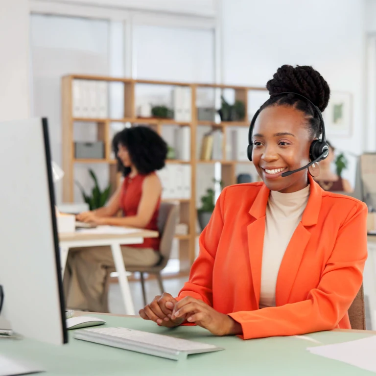 A smiling consultant with a headset sits at a desk in a modern office, providing customer support for two-pot savings withdrawals.