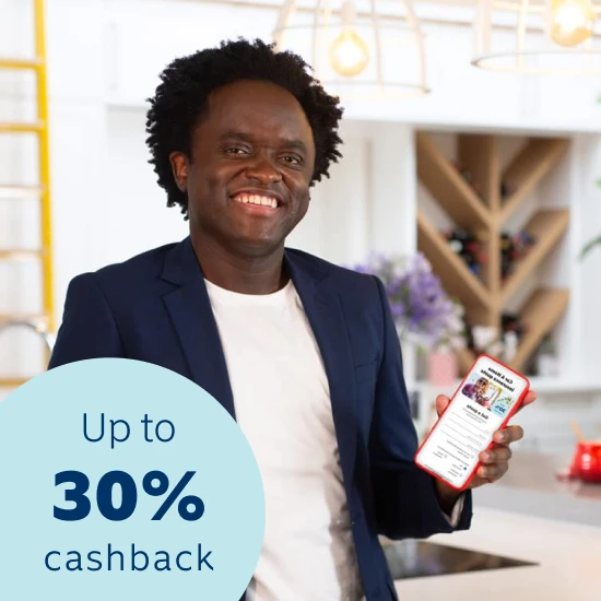 Comedian Tyson Ngubeni smiling in a house and displaying the Momentum App on this phone with a 30% cash back on car and home insurance premiums when joining Safety Returns.